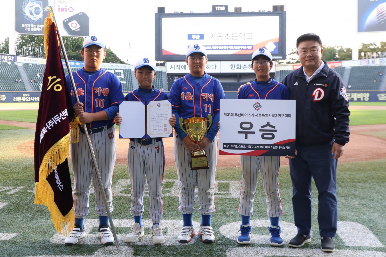 ‘2025 두산베어스기 어린이야구대회’ 초등부(12세 이하) 우승팀 가동초등학교가 18일 잠실구장에서 진행된 시상식에 참석했다. 김태룡 두산 단장(오른쪽)과 선수들이 기념촬영을 하고 있다. 사진제공｜두산 베어스