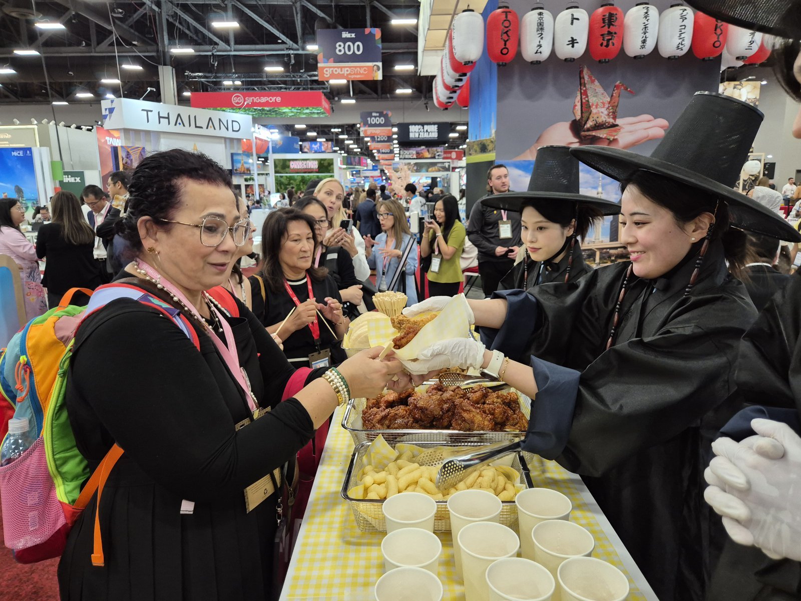 서울홍보관 관계자들이 ‘케이팝 데몬 헌터스’ 속 의상을 착용하고 참가자들에게 치킨과 맥주를 제공하고 있다