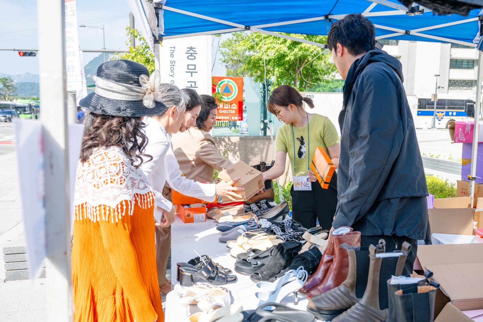 광화문원팀 바자회에 참가한 임직원들이 물건을 건네고 있다