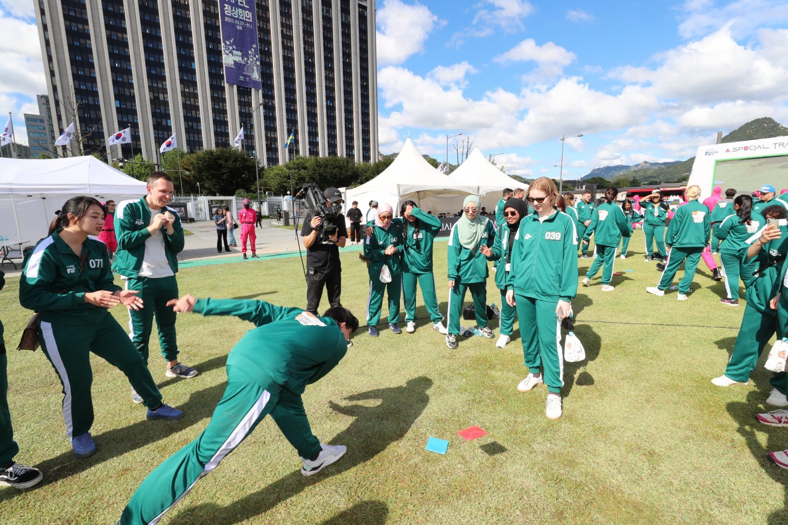 오징어 게임 핑크가드와 함께하는 여행 이벤트에서 참가자들이 조별 미션인 딱지치기를 즐기고 있다