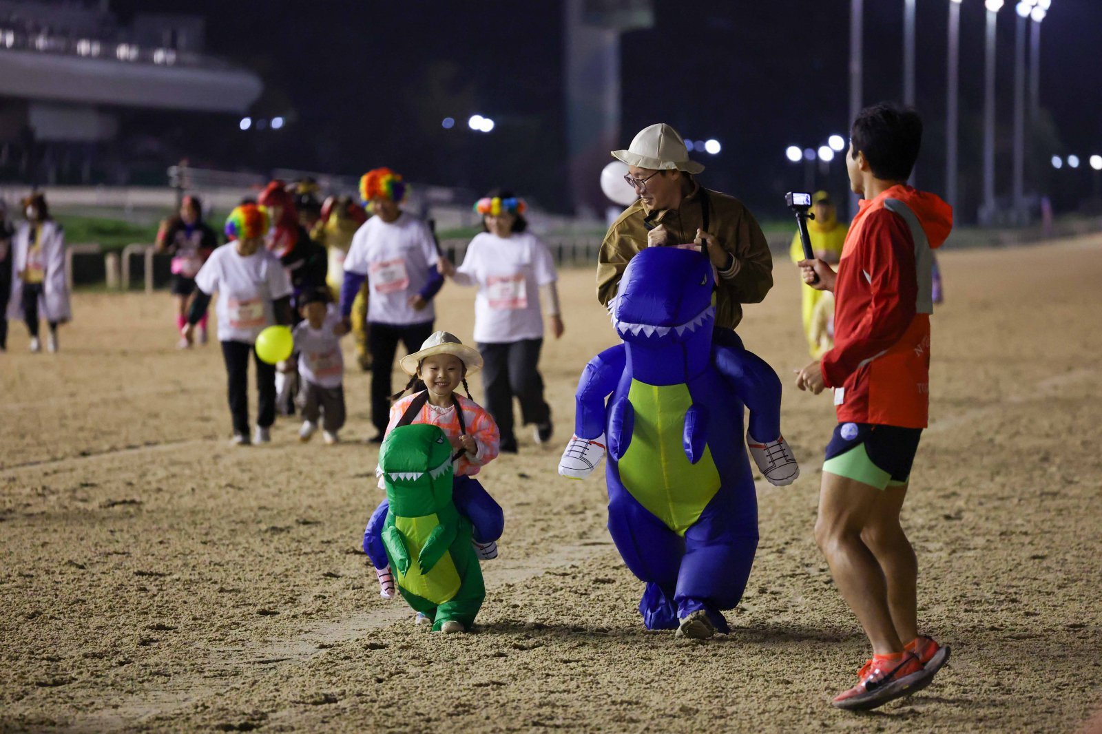 공룡 코스튬을 하고 경주로를 달리고 있는 한 가족.