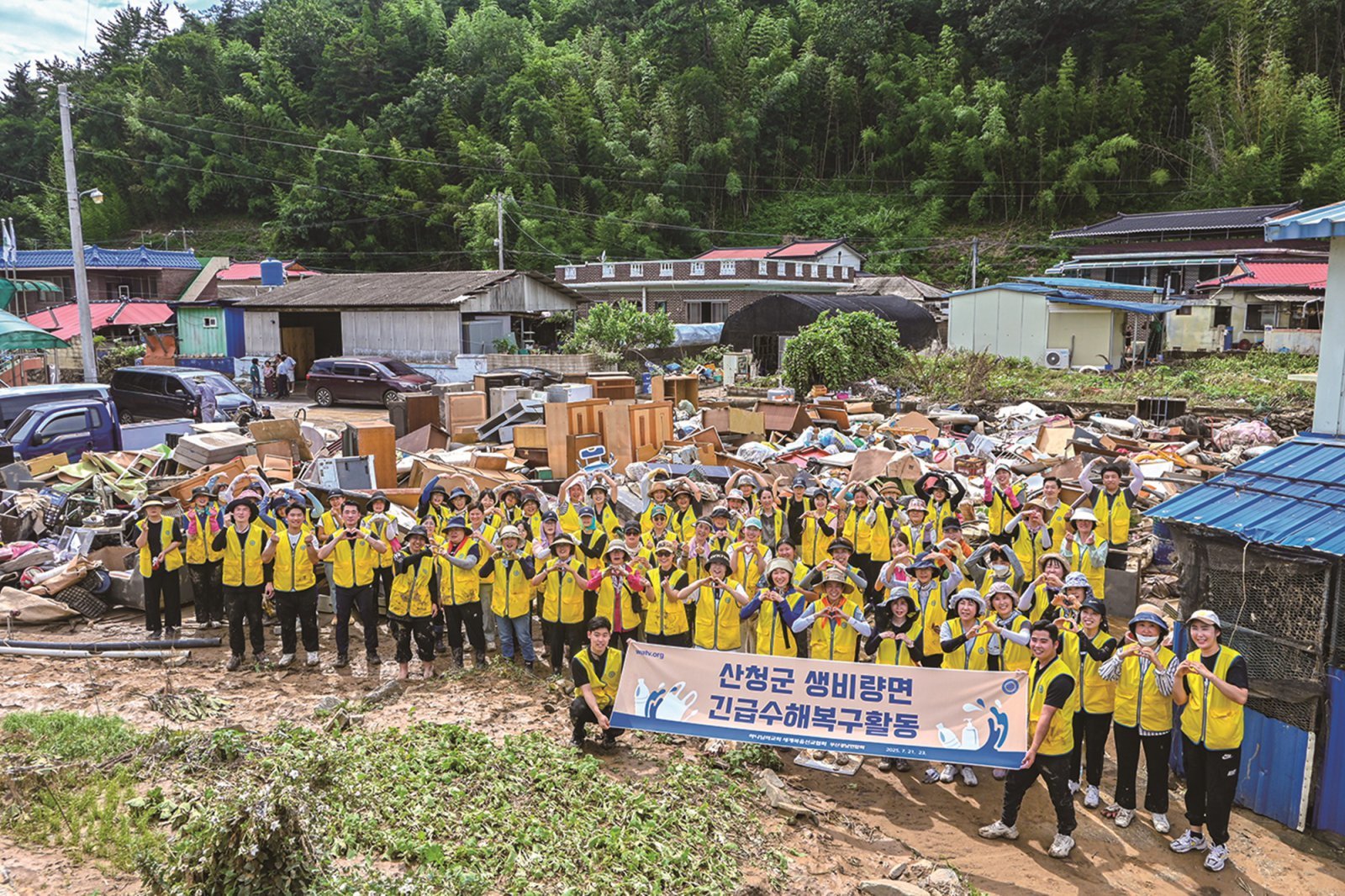 지난해 7월 경남권 일대 하나님의 교회 신자들이 산청군 수해복구 활동을 펼치며 구슬땀을 흘렸다. 봉사자들 뒤에 집 밖으로 꺼내진 장롱과 냉장고, 식탁, 장판 등 가재도구와 생필품이 쌓여 있다.