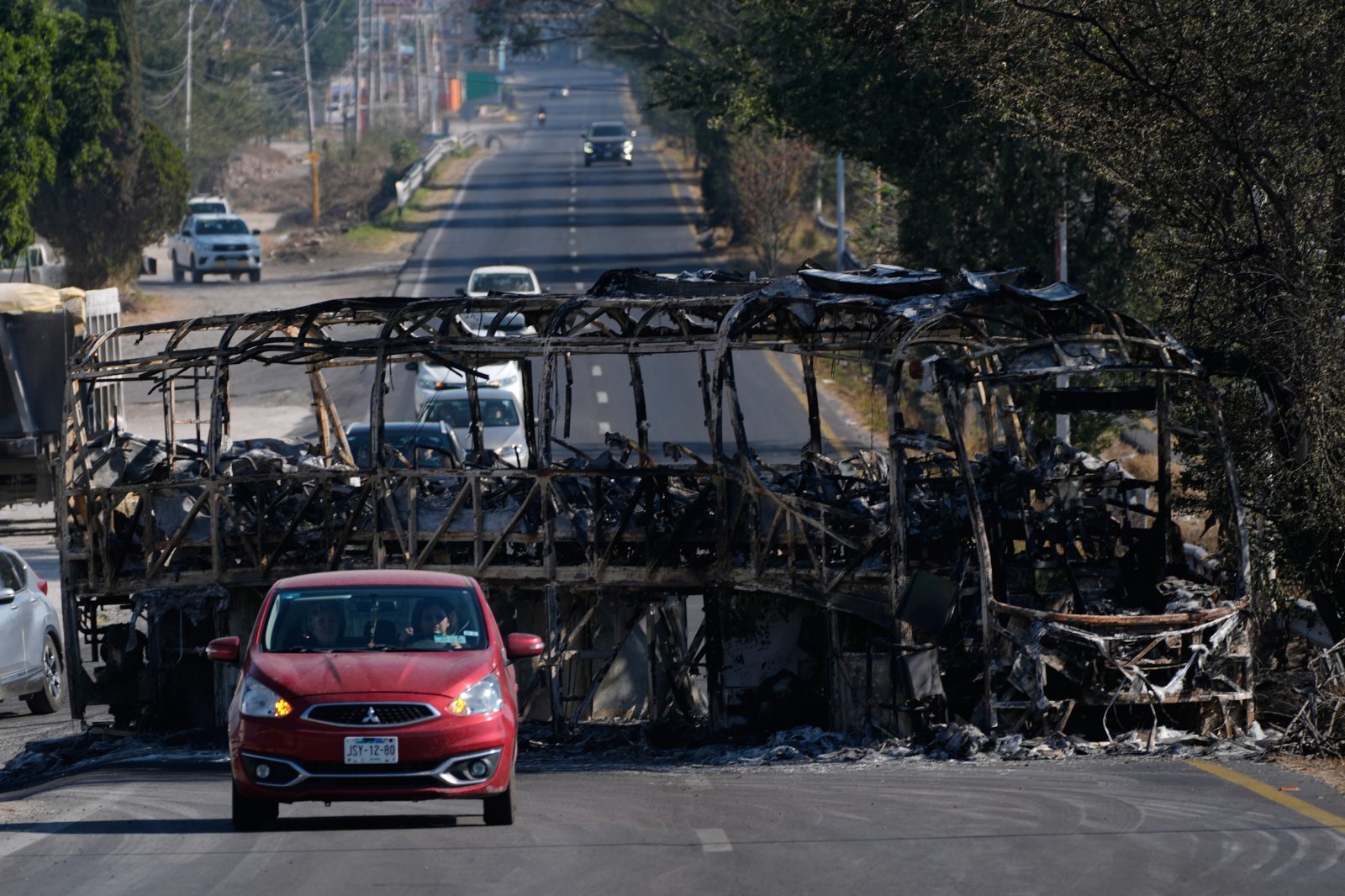 마약 카르텔 두목 네메시오 오세게라의 사망으로 유혈사태가 지속되는 멕시코 과달라하라의 도로에서 자동차가 불에 타 검게 그을린 채 도로를 막고 있는 버스를 지나치고 있다. FIFA가 과달라하라의 2026북중미월드컵 개최권 박탈까지 가능한 것으로 알려진 가운데 이곳에 베이스캠프를 차리고 조별리그 2경기를 치를 KFA도 촉각을 곤두세우고 있다. 과달라하라|AP뉴시스