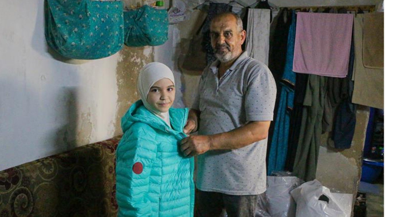 지진으로 피해를 입은 시리아 소녀가 영원무역그룹이 후원한 의류를 전달받는 모습