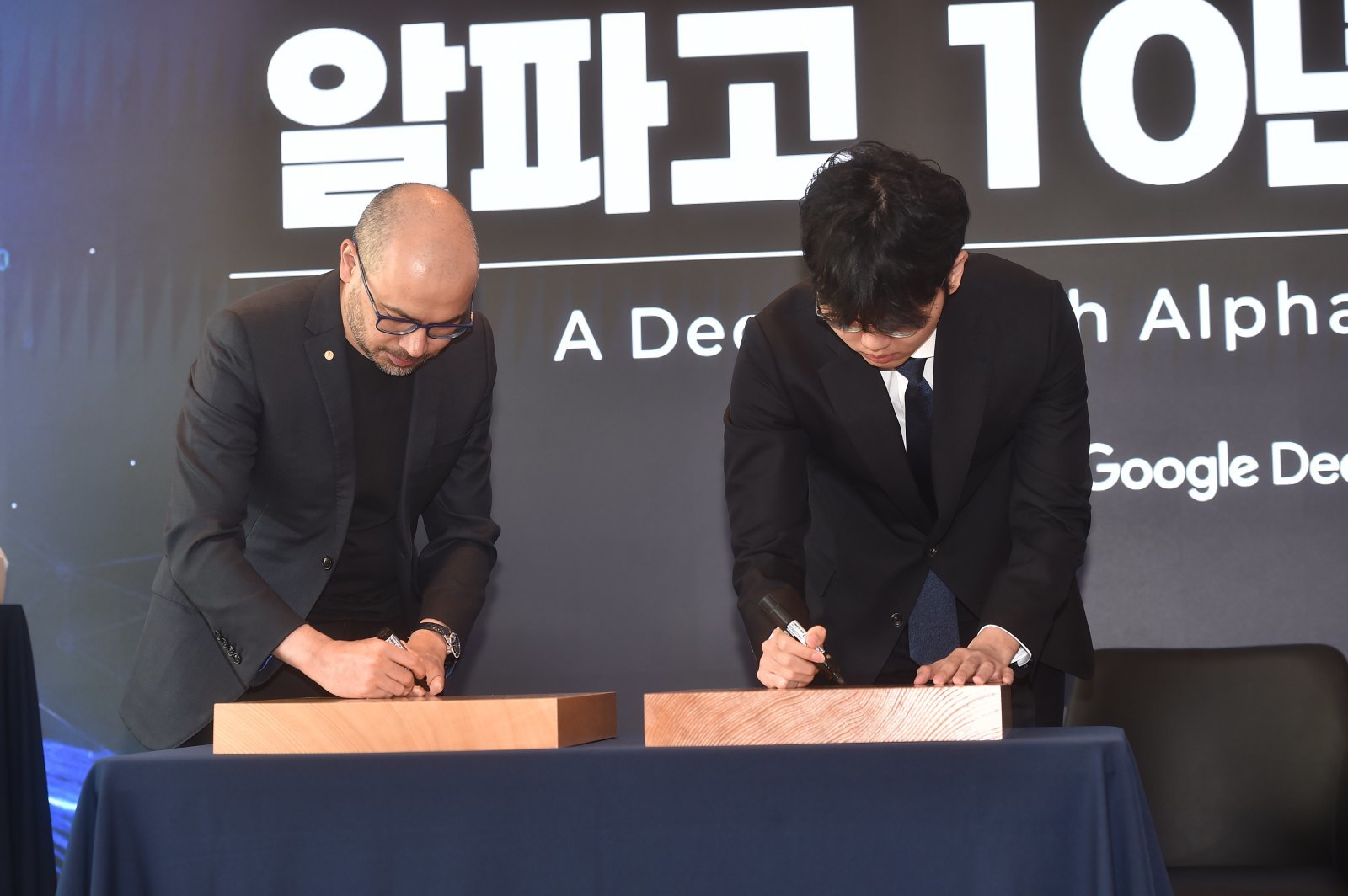 대국 후 바둑판에 사인을 하고 있는 데미스 허사비스 CEO(왼쪽)와 신진서 9단          사진제공 ｜한국기원