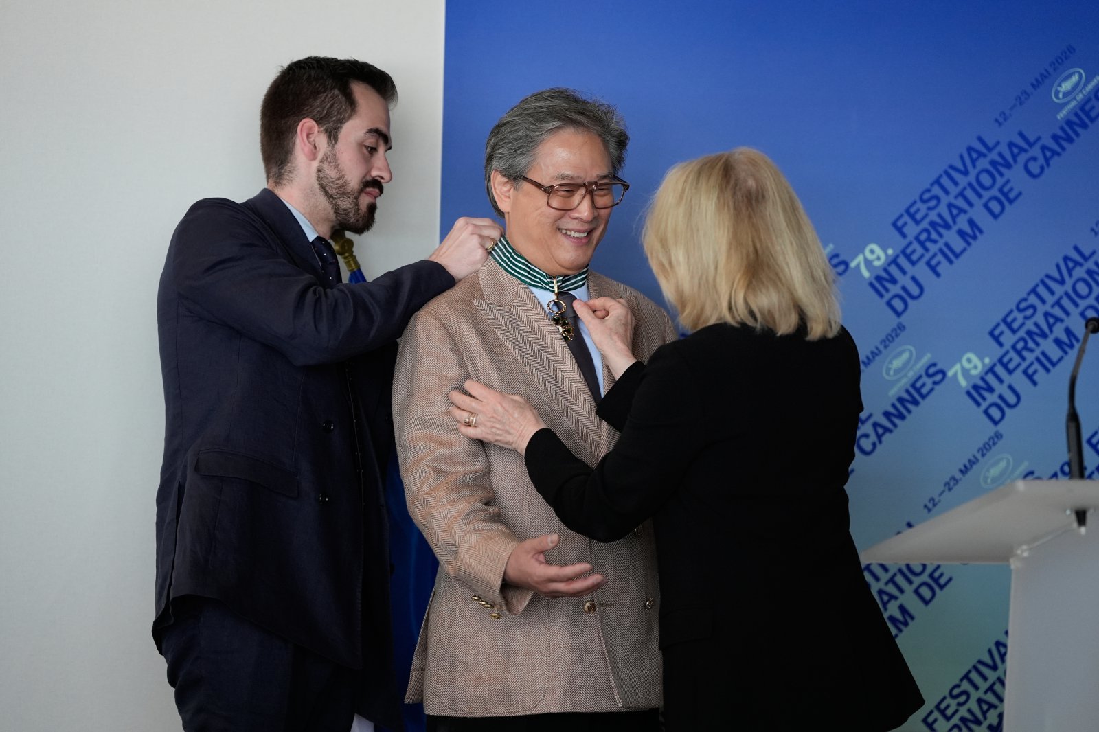 French Minister of Culture Catherine Pegard, right, presents jury president Park Chan-wook, centre, with The Order of Arts and Letters during the 79th international film festival, Cannes, southern France, Sunday, May 17, 2026. (AP Photo/John Locher)