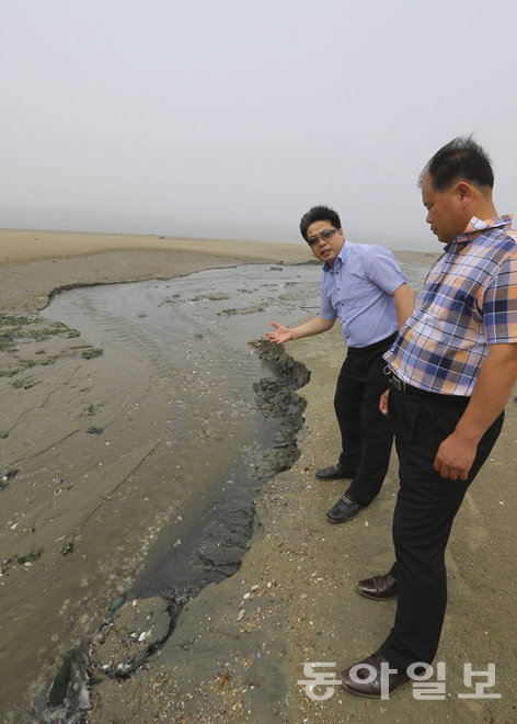 ‘태안 사설 해병대 캠프 참사’의 유족 이후식 씨(고 이병학 군 아버지·왼쪽)와 김영철 씨(고 김동환 군 아버지·오른쪽 앞)가 14일 사고 해변을 찾았다. 유족들은 “모래들이 움푹 파인 것은 인근 해수욕장으로 모래를 나르는 불법공사 때문에 생겼다”고 강조했다. 태안=원대연 기자 yeon72@donga.com