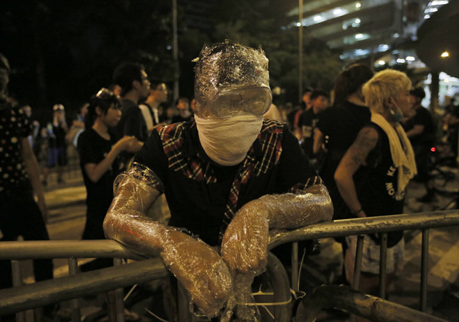 지난달 29일 홍콩 중심가에서 시위를 벌이던 한 젊은 남성이 경찰이 쏜 최루탄을 견디기 위해 얼굴과 팔에 비닐 랩을 여러 겹 감고 바리케이드 앞에 서 있다. 홍콩=AP 뉴시스