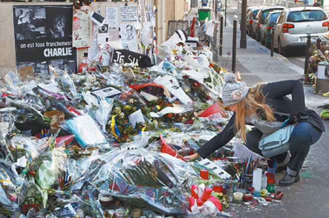 7일 프랑스 파리 11구에 위치한 풍자 주간지 ‘샤를리 에브도’ 본사 건물 앞에서 한 젊은 여성이 헌화하고 있다. 한 달 전 이슬람 극단주의자들의 연쇄 테러로 이곳의 기자 등 17명이 숨진 것을 기리기 위한 시민들의 꽃이 수북이 쌓여 있다. 파리=AP 뉴시스