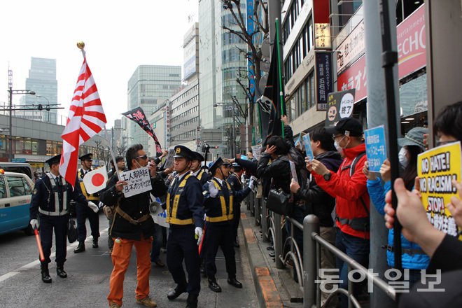 6일 오후 일본 도쿄 긴자 거리에서 욱일기를 든 우익 혐한 시위 참가자가 혐한 반대 시위대와 신경전을 벌이고 있다. 이날 시위에서는 몸싸움도 벌어졌다. 도쿄=장원재 특파원 peacechaos@donga.com