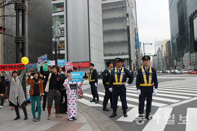6일 오후 일본 도쿄 긴자 거리에서 욱일기를 든 우익 혐한 시위 참가자가 혐한 반대 시위대와 신경전을 벌이고 있다. 이날 시위에서는 몸싸움도 벌어졌다. 도쿄=장원재 특파원 peacechaos@donga.com