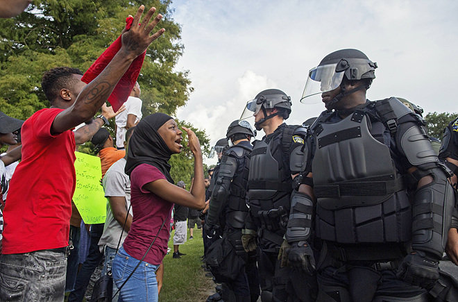 9일 미국 루이지애나 주 배턴루지의 경찰청사 앞에서 백인 경찰관의 흑인 사살에 항의하는 시위를 벌이던 참가자들이 전투경찰들에게 구호를 외치고 있다. 이날 시위에는 급진적 흑인인권 단체인 ‘뉴 블랙팬서 당’의 회원들도 참여했다. 배턴루지=AP 뉴시스