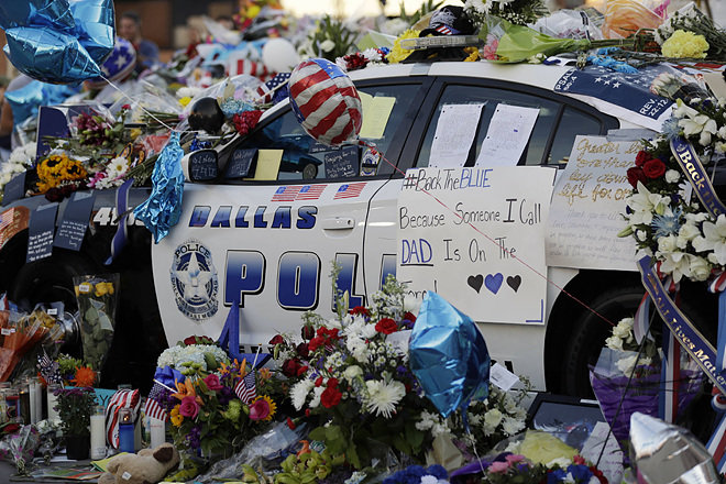 9일 미국 텍사스 주 댈러스 경찰청 앞에 주차된 경찰차가 7일 총격 사건으로 숨진 경찰관 5명을 추모하기 위해 시민들이 놓고 간 꽃과 편지들로 뒤덮였다. 뒤쪽 차문에 경찰을 지지한다는 내용의 문구(Back the Blue)가 보인다. 댈러스=AP 뉴시스